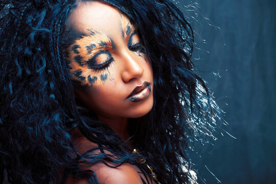 beauty afro girl with cat make up, creative leopard print on face closeup halloween woman