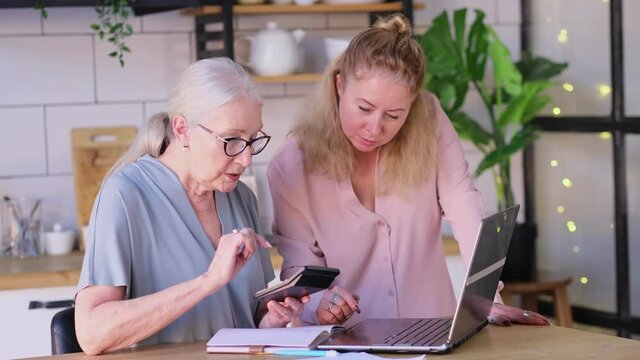 Woman teaching senior mother to use internet at home. Senior woman with her daughter looking at modern gadget indoors. close up view. Slow motion nvideo. stock footage