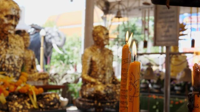 4K Orange candle with frame light in temple with buddha statue background. Concept of life, hope, belief, buddism religion.