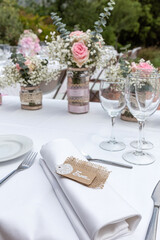 Wedding table decorated with bouquet of pink flowers and wine glasses.