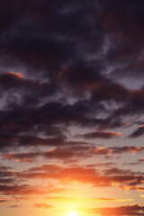 Epic dramatic sunset, sunrise on storm sky with dark blue violet clouds, orange yellow sun and sunlight