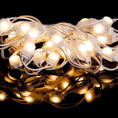 White warm christmas LED lights glowing with reflection on black background