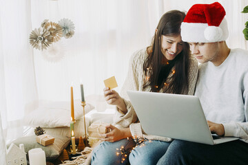 Happy couple buying gifts online using laptop and credit card. Christmas sale and Black Friday