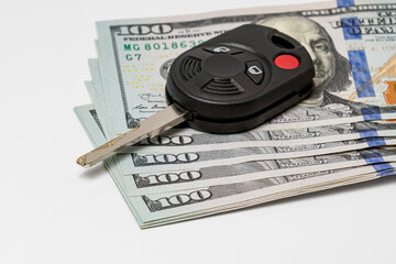 Car key and 100 dollar bills cash. Concept of vehicle purchase cost, loan, repair, maintenance and expenses