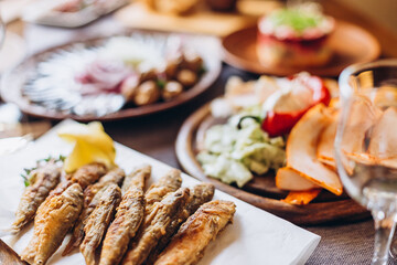 home wooden table covered with plates with various delicious dishes in the Slavic style: sourdough, salted and fried fish, potatoes, fried meat and salads