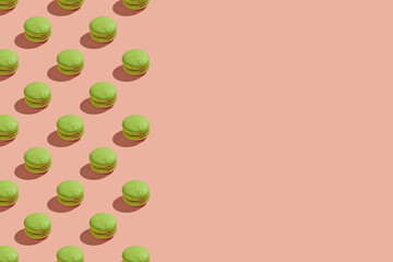 Green macaroons with shadows on colored background. Trendy minimal pattern with copy space. French cookies macarons on a pink pastel background. Delicious  french dessert. Creative modern background