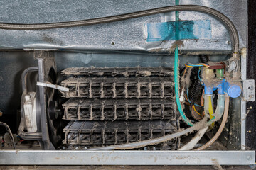 Dirty refrigerator condenser cooling coils covered in dust and pet hair. Concept of household...