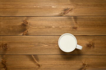 White cup of milk on wooden table with copy space, top view. Natural organic product concept.