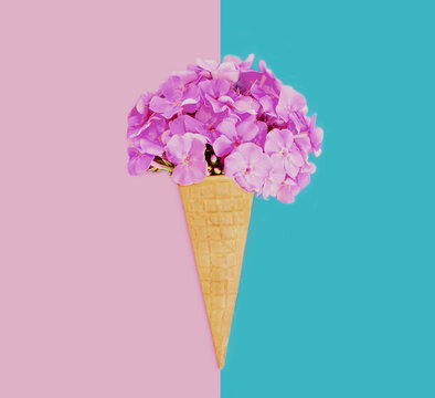 =Stylish image of cone with pink flowers as ice cream over a blue background