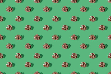 Pine cone on a green pastel background. Christmas decorations. Minimal composition seamless pattern background. Christmas and New year concept. Top view, flat lay