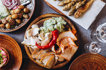 a large clay plate with a national Slavic delicacy - thinly sliced lard with spices on the table among other dishes. Concept for restaurant or menu