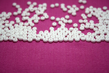 White beads spread on pink background.