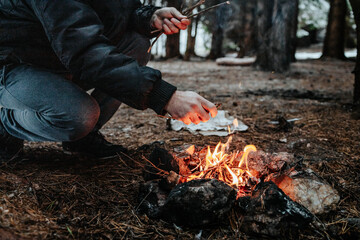 Close-up of man making bonfire. Outdoors grainy photo