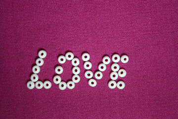 Fototapeta na wymiar White beads spread on pink background.