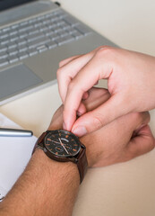 man's hands adjusting the schedule on watch, while working in the office.