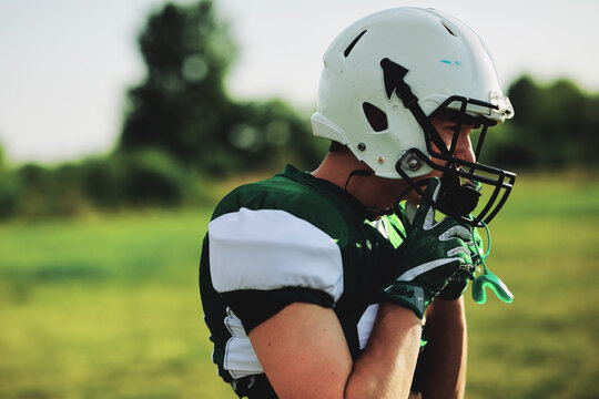 Football player adjusting the fit of his helmet during practice - Powered by Adobe