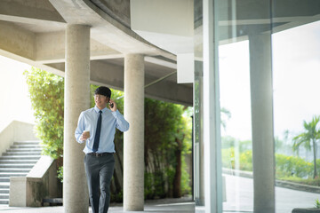 Asian business man using mobile phone while walking in the city street..