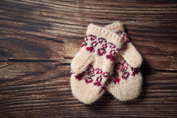 Obraz na płótnie Canvas Two wool baby Christmas mittens decor on the old wooden planks background