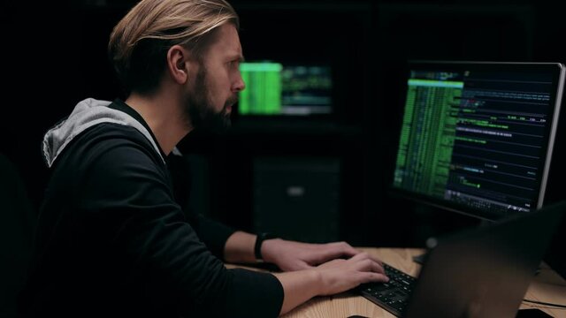 Middle-aged man in hoodie working on computer at night, software engineer coding