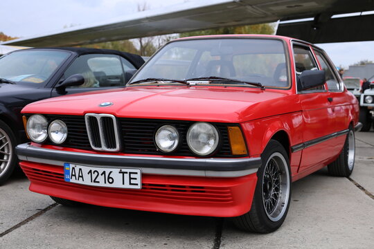 Front view of a German BMW e21 318i car, red coupe, with a license plate.