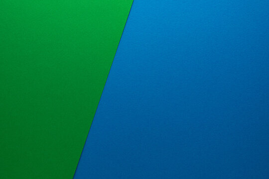 Beautiful background of two unequal parts of colored paper blue and green. Sheets of blank blue and green paper with fine texture devided  by a sloping border.
