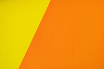 Beautiful paper background of two unequal parts yellow and orange. Sheets of blank yellow and orange paper with fine texture separated by a sloping border.