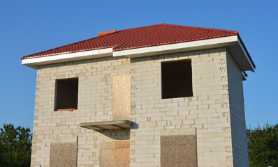 Winterizing and conservation of unfinished house under construction by closing doorway and window openings with plywood OSB boards to protect the building from snow and rain water damage in winter.