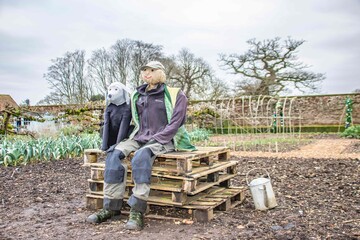 scarecrow sitting with dog in garden