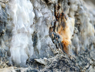Diverse colored quartz rock in cut of the earth. Deposits of gray, white, orange quartz. Untreated semi-precious stones of  chlatedony variety in various stone deposits and layers of different rocks.