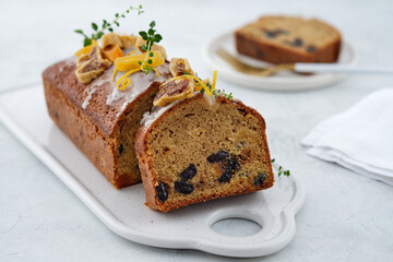 Beautiful delicious homemade Christmas dried fruit cake on grey table with decorating items for celebrating festive season.