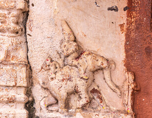 Hampi, Karnataka, India - November 4, 2013: Virupaksha Temple complex. Closeup of damaged elephant with 2 figures on top mural on red and beige wall. Walk right.