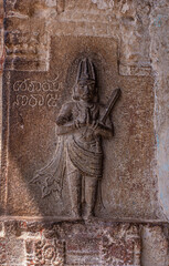 Hampi, Karnataka, India - November 4, 2013: Virupaksha Temple complex. Closeup of brown stone sculpted mural depicting important official man on wall. Seems to hold sword.