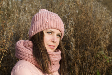 A girl in autumn clothes among the dried tall grass. Walking in nature in the park.