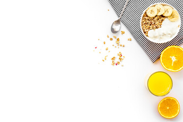 granola with banana slices and orange juice for breakfast on blue background top view copyspace