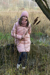 A girl in autumn clothes with a bouquet of reeds in her hands. Walking in nature in the park.