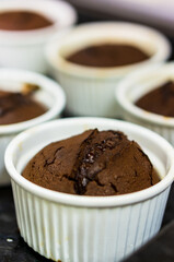 Vertical selective focus shot of chocolate puddings in white cups
