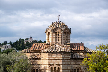 Greek Orthodox church in Thissio area, Athens, Greece. Flock of pigeons sitting on the dome,  cloudy sky background