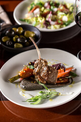 Rack of Lamb ribs garnished with baby carrots on wooden table at restaurant