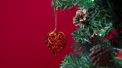 Heart of a Christmas toy hung on a Christmas tree on a red background close-up