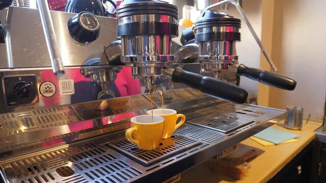 Barista making coffee two small portion yellow cups on expresso maching in a bar