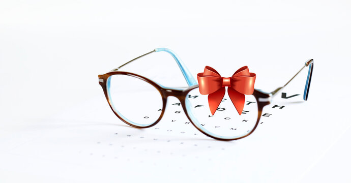 Occhiali da vista e fiocco in nastro rosso isolato su sfondo bianco. Carta regalo occhiali da vista di Natale.