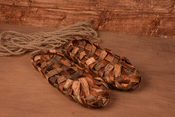 Birchen woven bast shoes hang on a log wall.