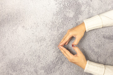 Female hands making sign Heart by fingers on the table. Love concept on Valentine day.