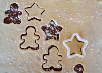 Christmas cookie dough stretched and cut with molds in the shape of a gingerbread man and stars