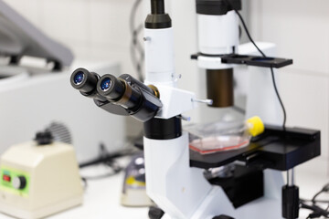 Fototapeta na wymiar Microscope with two lenses inside medical laboratory. Close-up of scientific device for analyzing chemical samples. Concept of research and experimenting in hospital environment.