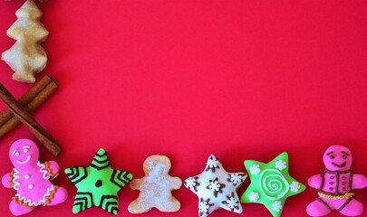 Christmas composition: lower frame of Christmas cookies and cinnamon sticks on red background