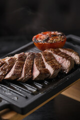 Meat steak slices on black barbecue board