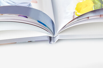 Open, high quality photo book with hardback and colorful pages on white studio background. Close...