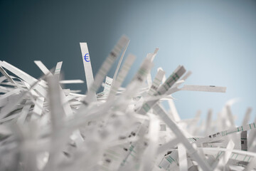 A pile of shredded paper strips and on one strip a Euro symbol is printed.