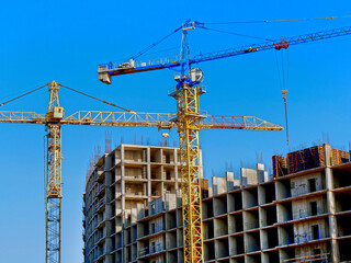 Two cranes near building. Concrete building under construction.